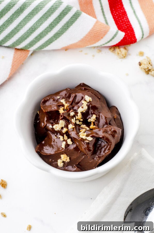 bowl of chocolate avocado pudding with a spoon beside it