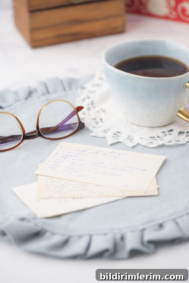 a pile of old recipe cards with a cup of coffee and pair of glasses beside it. Vintage cookbooks are in the background.
