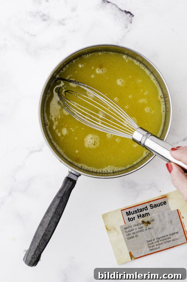 Ingredients for homemade mustard sauce for ham being whisked together in a saucepan.