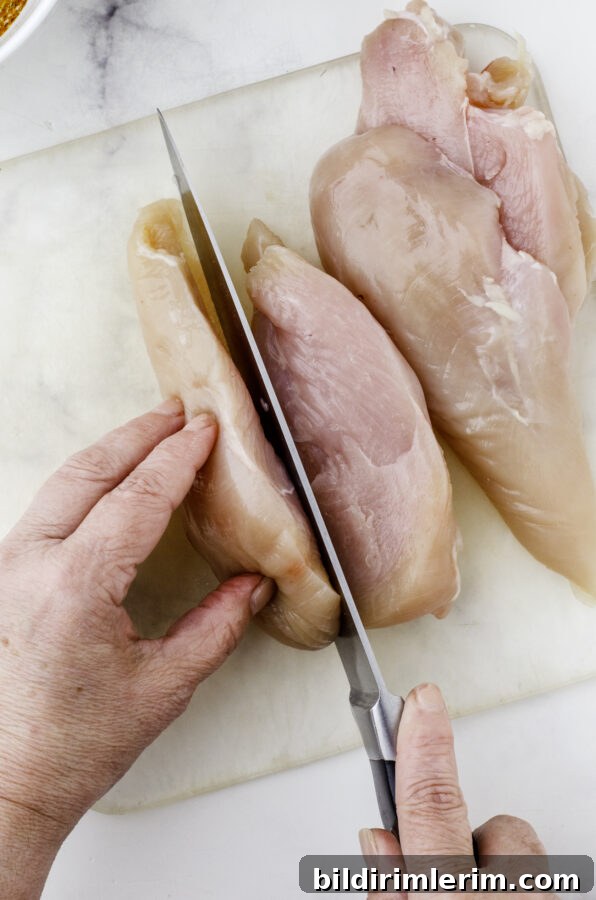 Slicing a chicken breast in half to make it thinner in preparation for chicken breast mexican marinade.