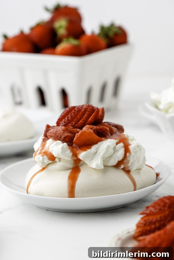 Four individual strawberry pavlovas on a serving plate