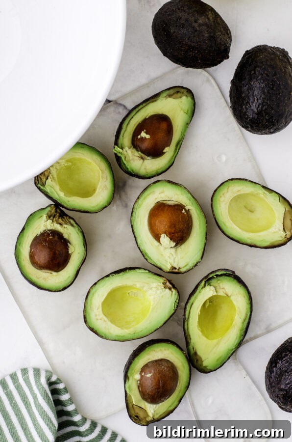 Avocados cut in half and sitting on a cutting board.