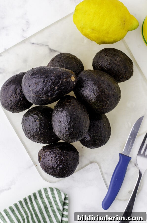 A pile of avocados and a lemon sitting on a cutting board.