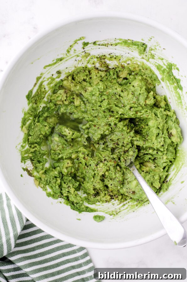 Avocados after they have been mashed with a fork in a large bowl.