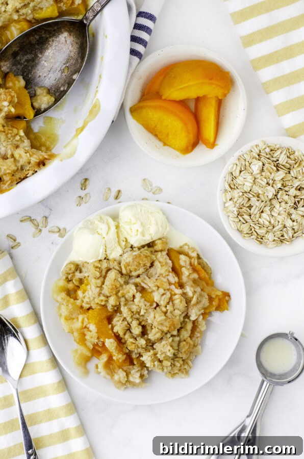 A serving of peach crisp with scoops of ice cream beside it on a dessert plate, with a pan of peach crisp with a scoop out of it above the dessert plate.
