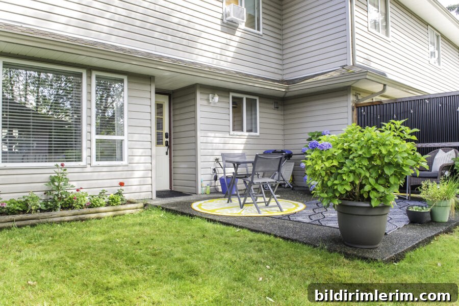 A small concrete slap patio outside a townhouse with a flower bed on one side.