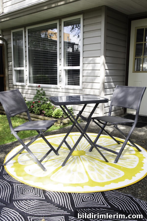 A 3 piece bistro table set sitting on a round outdoor rug.