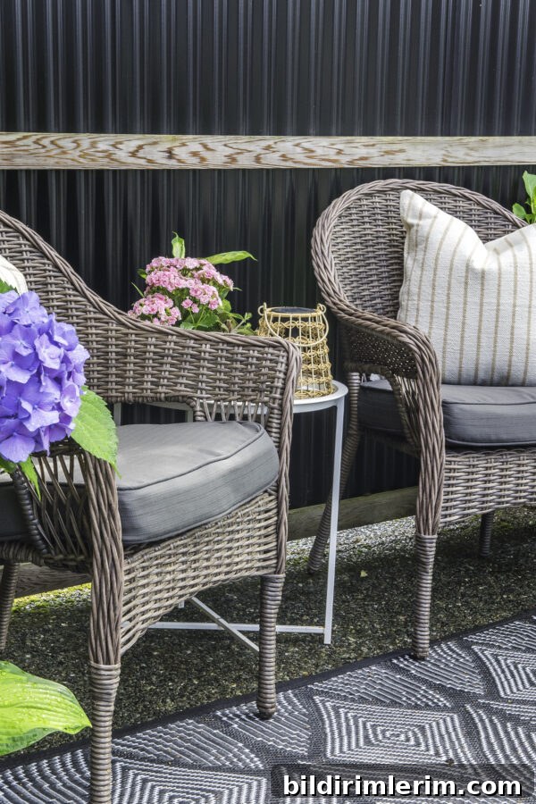 Two patio chairs with cushions with a side table between.