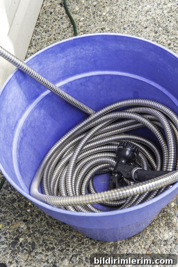 A metal garden hose wound up in a large plastic planter.