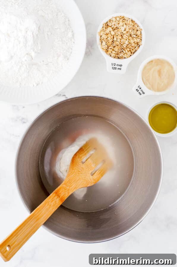 Water, sourdough starter, and salt in the bowl of an electric mixer ready to be stirred.