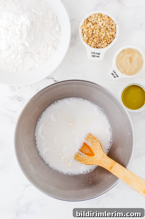 The white, milky liquid of the sourdough starter and water after it has been mixed together in the bowl of an electric mixer.