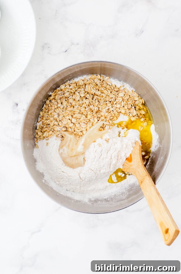 All the ingredients of honey oat sourdough bread in the bowl of an electric mixer before it is mixed together.
