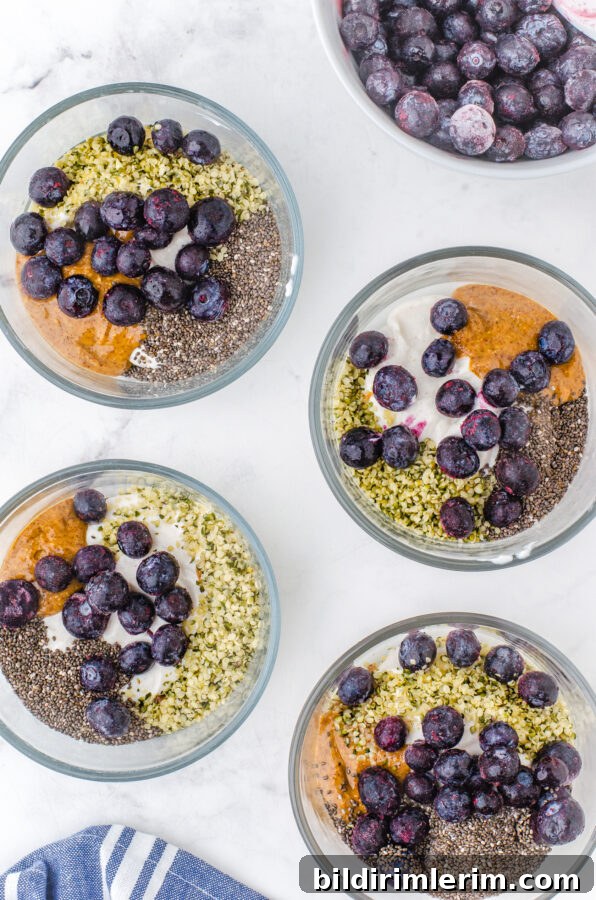 Make-Ahead Yogurt Bowls for Quick Grab-and-Go Breakfasts 7 4 serving bowls with greek yogurt almond butter, chia seeds, hemp seeds and frozen blueberries in them.