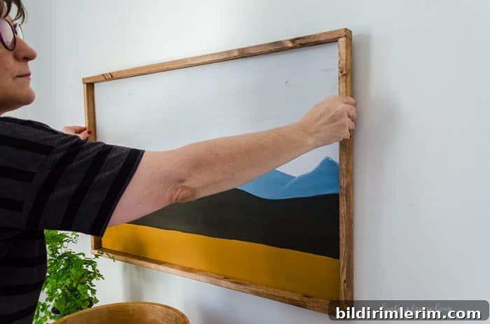 How to Hang Wall Decor: Tips and Practical Hacks 2 woman hanging a picture on the wall