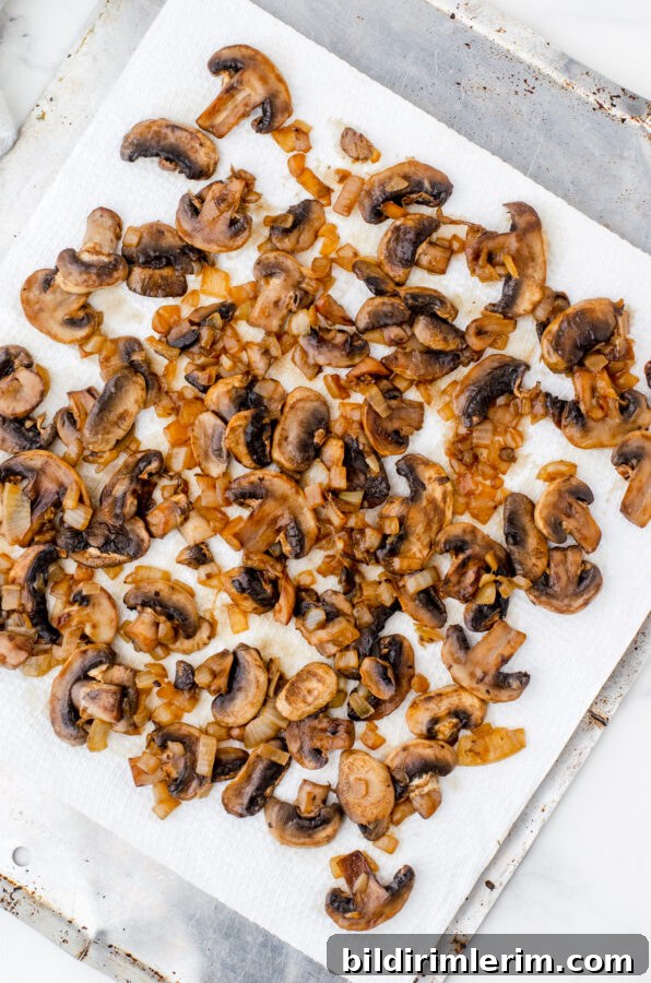 Sautéed mushrooms and diced onions on a paper towel lined pan