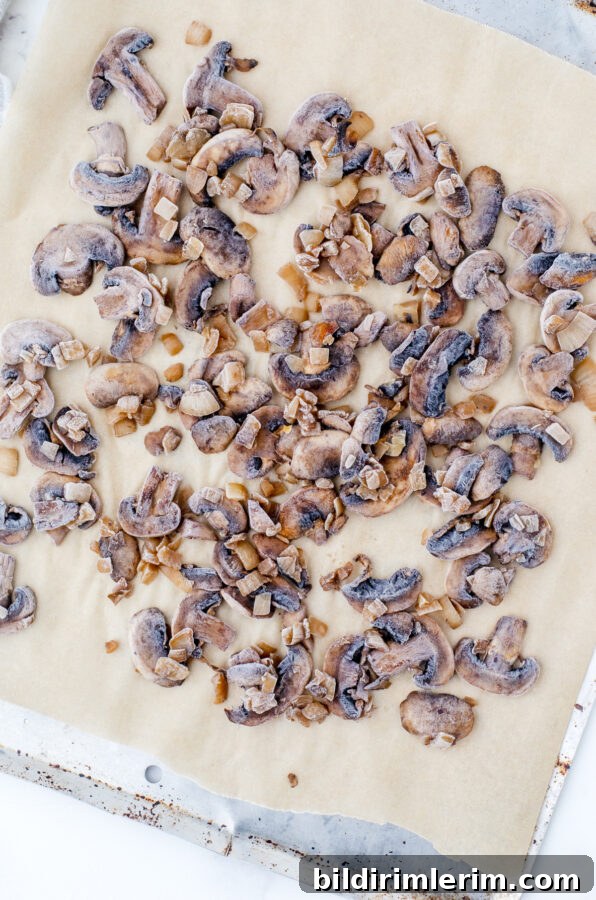 Frozen mushrooms in a single layer on a parchment lined pan.