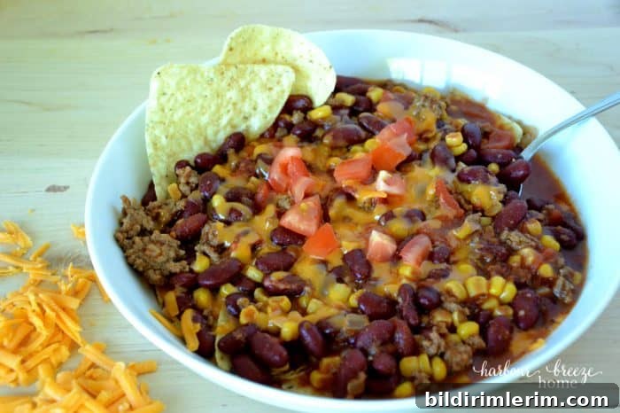 a bowl of taco soup with taco chips and grated cheese on the side