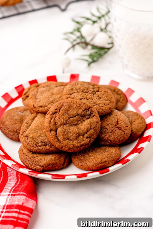 A plate of soft and chewy gingersnaps with a glass of milk beside it.