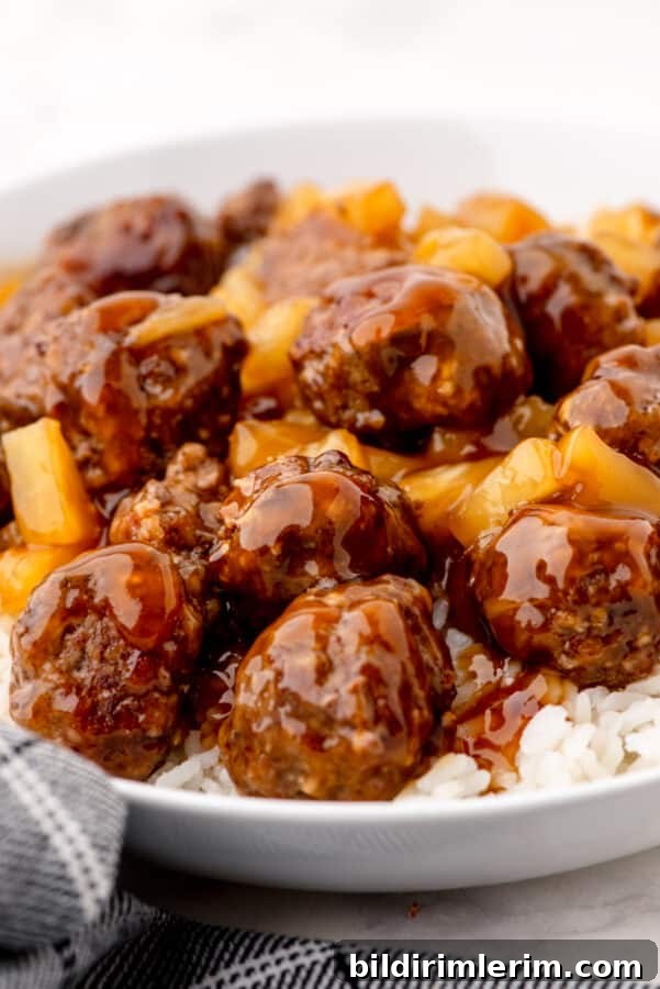 Waikiki Sweet and Sour Meatball Recipe with Pineapple Tidbits 2 Sweet and sour Waikiki meatballs over a bed of rice in a large bowl.