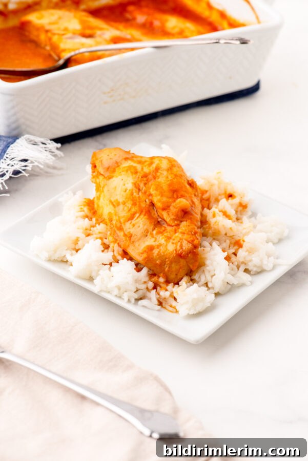 A piece of apricot chicken on a bed of rice on a white plate.