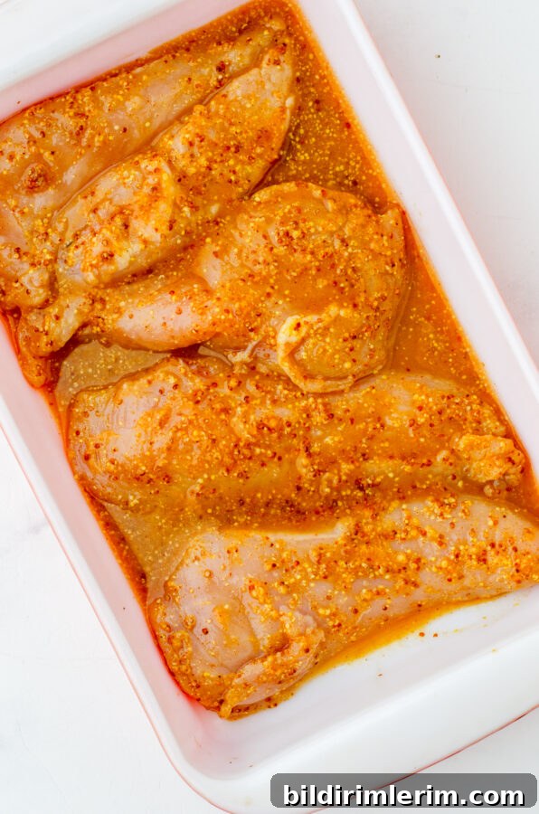 Chicken with marinade in a baking dish.