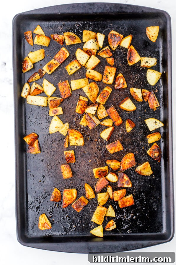 Crispy Oven-Roasted Diced Potatoes Recipe 6 Roasted potatoes on a stoneware pan after they have been baked.