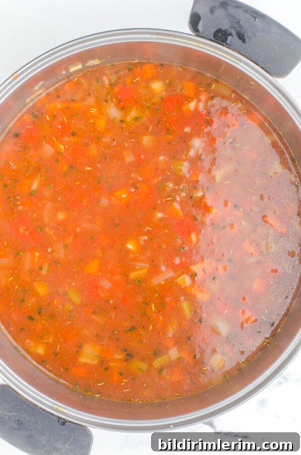 Hamburger rice soup with all the ingredients stirred together in a large stock pot - before it is simmered and cooked through.