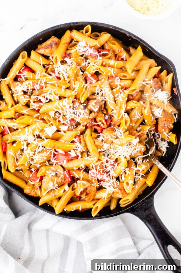 Cajun chicken pasta in a skillet with cheese sprinkled over the top.
