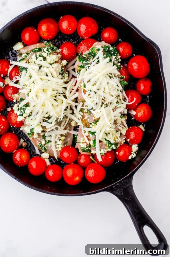 Hasselback chicken placed over tomatoes in a cast iron pan.
