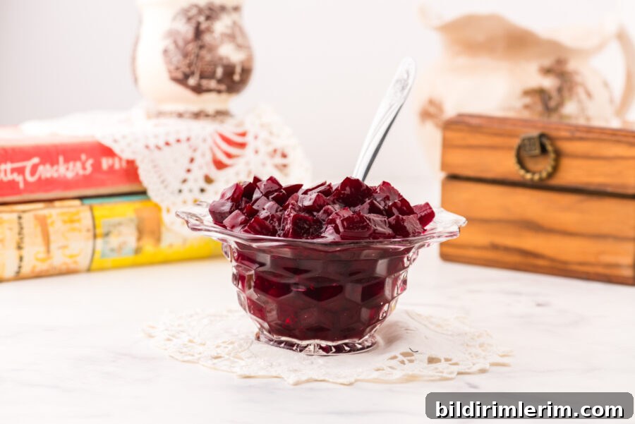 A bowl of harvard beets on a crocheted doily with antique cookbooks and an antique recipe box behind it.