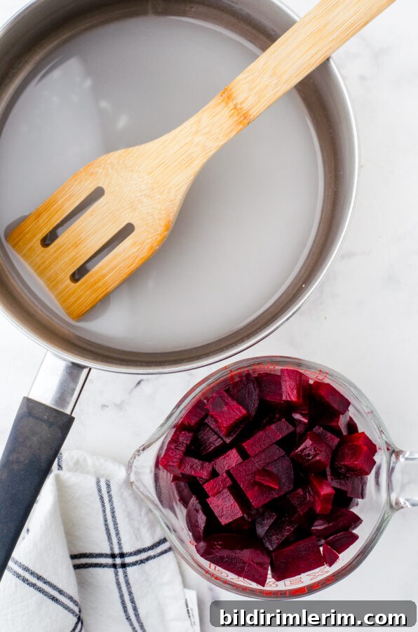 A saucepan with harvard beets sauce ingredients in it with cubed beets beside it.