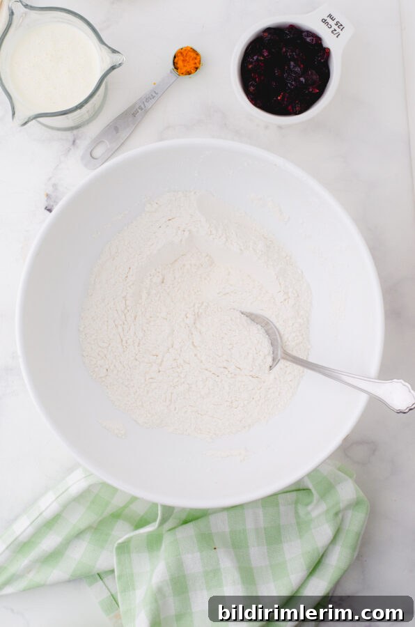 Dry ingredients for cream scones in a mixing bowl being stirred together.