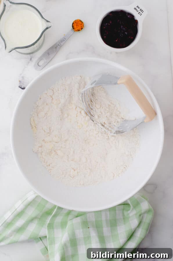 Butter being cut into the dry ingredients with a pastry blender