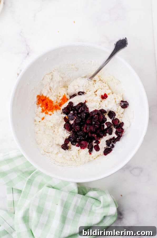 Cranberries and orange peel being added to cream scones.