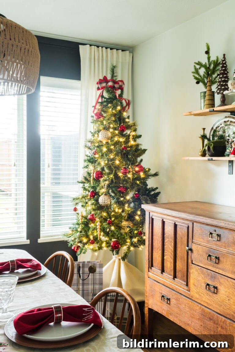 Christmas tree on a box beside an antique buffet