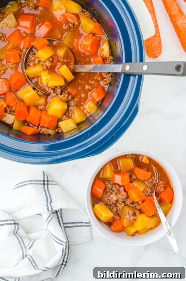 Slow Cooker Hamburger Stew Recipe 6 A crock pot full of hamburger stew with a bowl full of it served with a spoon in it.