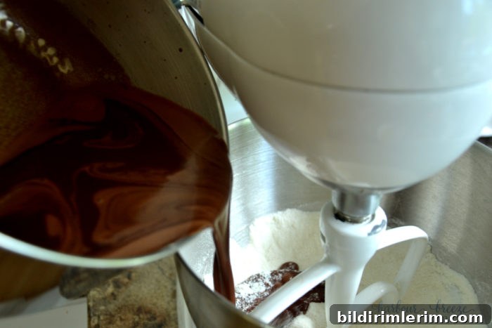 pouring hot ingredients into a mixing bowl with flour to make texas sheet cake brownie batter