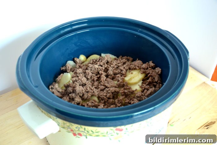 browned ground beef layered on top of potatoes in crock pot