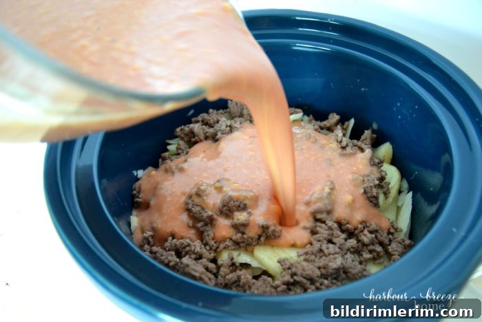 liquid being poured over the layers of ingredients in the crock pot