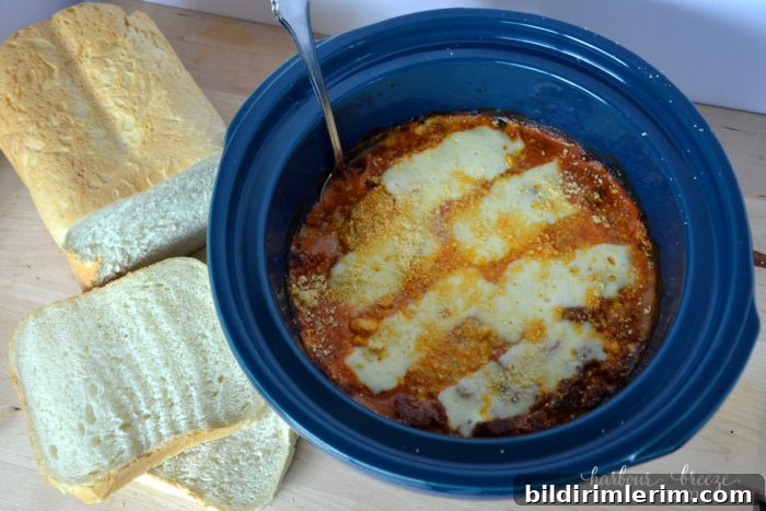 Potato Pizza Bake in the crock pot with melted cheese on top with fresh bread slices on the side