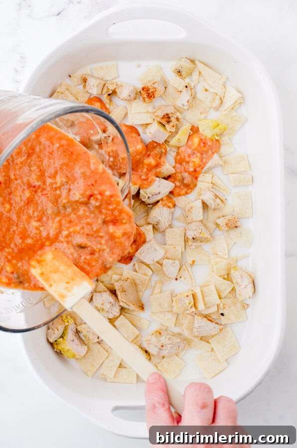 Cheesy One-Pan Mexican Chicken Casserole 4 A woman pouring sauce over the layers of Mexican chicken casserole in a baking dish.
